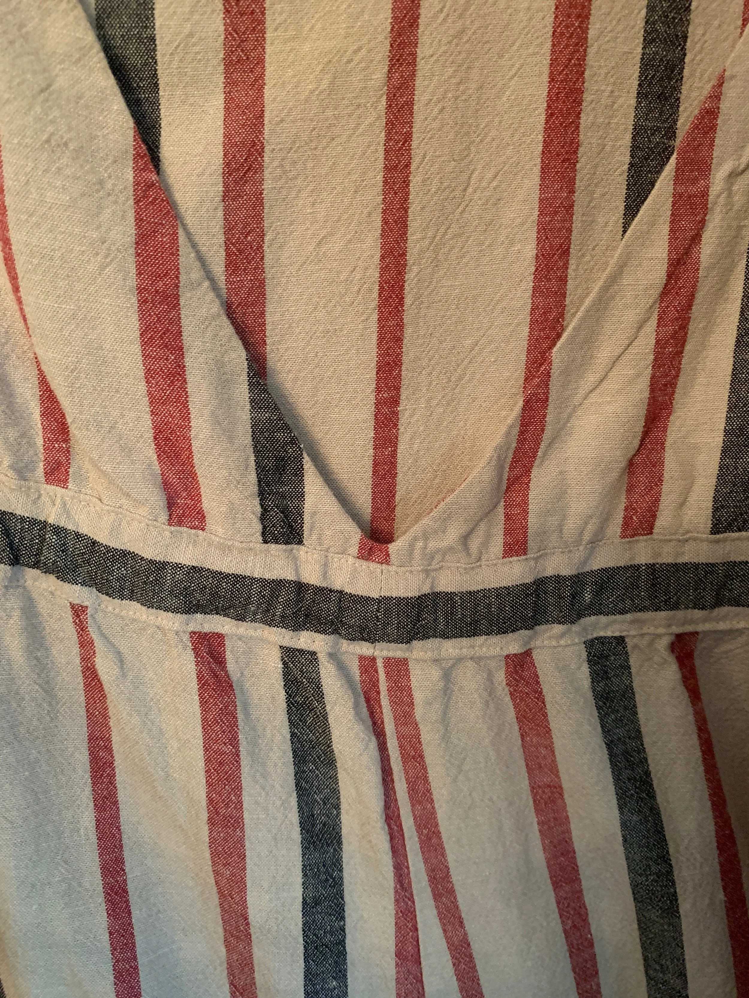 Close-up of a striped fabric garment with red and navy stripes on a cream background.